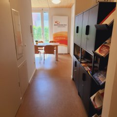 Eingangsbereich des Seniorenbüros Neufahrn mit Blick auf den Aufenthaltsraum mit Tischen und Stühlen, sowie Prospektständern auf der rechen Seite.