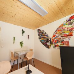 Blick auf ein Kunstwerk der vhs Neufahrn-Hallbergmoos im Beratungsbüro des Seniorenbüros Neufahrn das aus zwei überlebensgroßen Flügeln aus bunten Papierfedern besteht und als Selfie-Station gedacht ist. Ein Flügel ist dunkel gehalten, ein Flügel ist hell gestaltet.