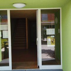 Verglaster Hauseingang des Seniorenbüro Neufahrn mit Öffnungszeiten-Tafel und informativen Plakaten auf der rechten Seite neben der Tür.